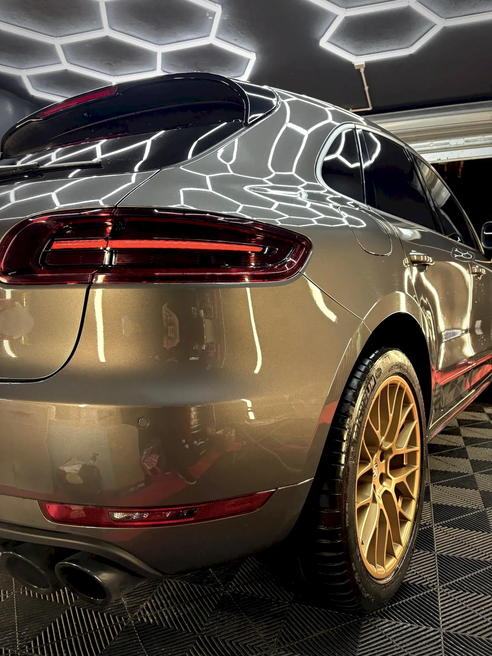 Arrière d'un Porsche Macan gris aux jantes dorées sous l'éclairage hexagonal de l'atelier DiamantClean à Ajaccio
